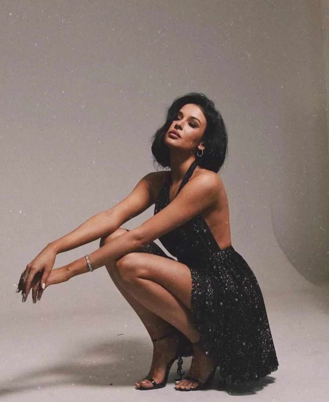 Fashion Model Squatting in a Black Dress And Heels Wallpaper