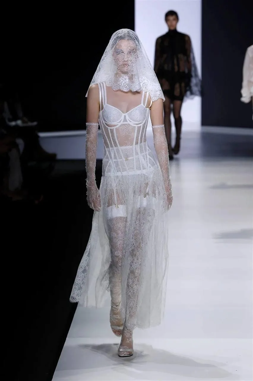 Fashion model walking runway in a sheer bridal inspired gown