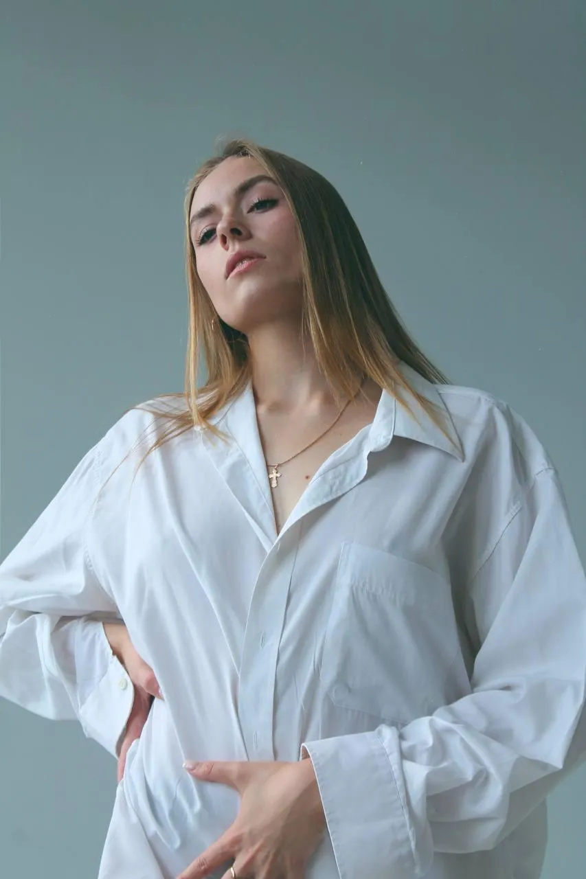 Fashion woman in an oversized white shirt posing indoors