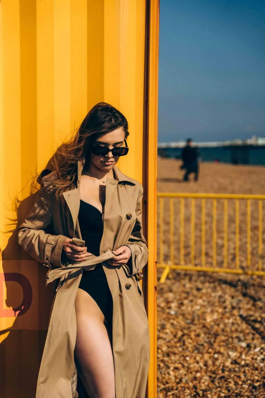 Fashionable Woman in a Trench Coat Sitting Near the Beach