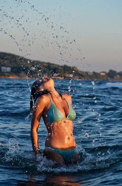 Fit woman in a bikini playing in the water at the seashore