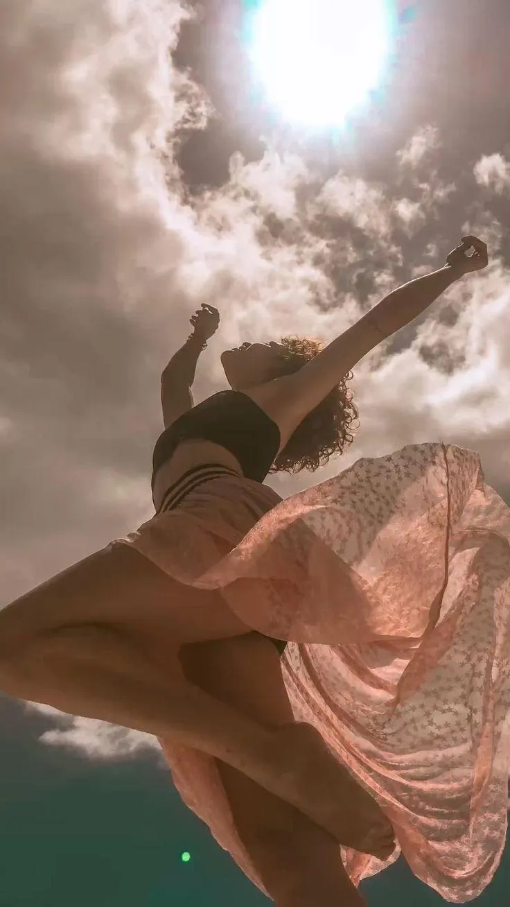 Flowing dress and dynamic jump under a bright summer sky