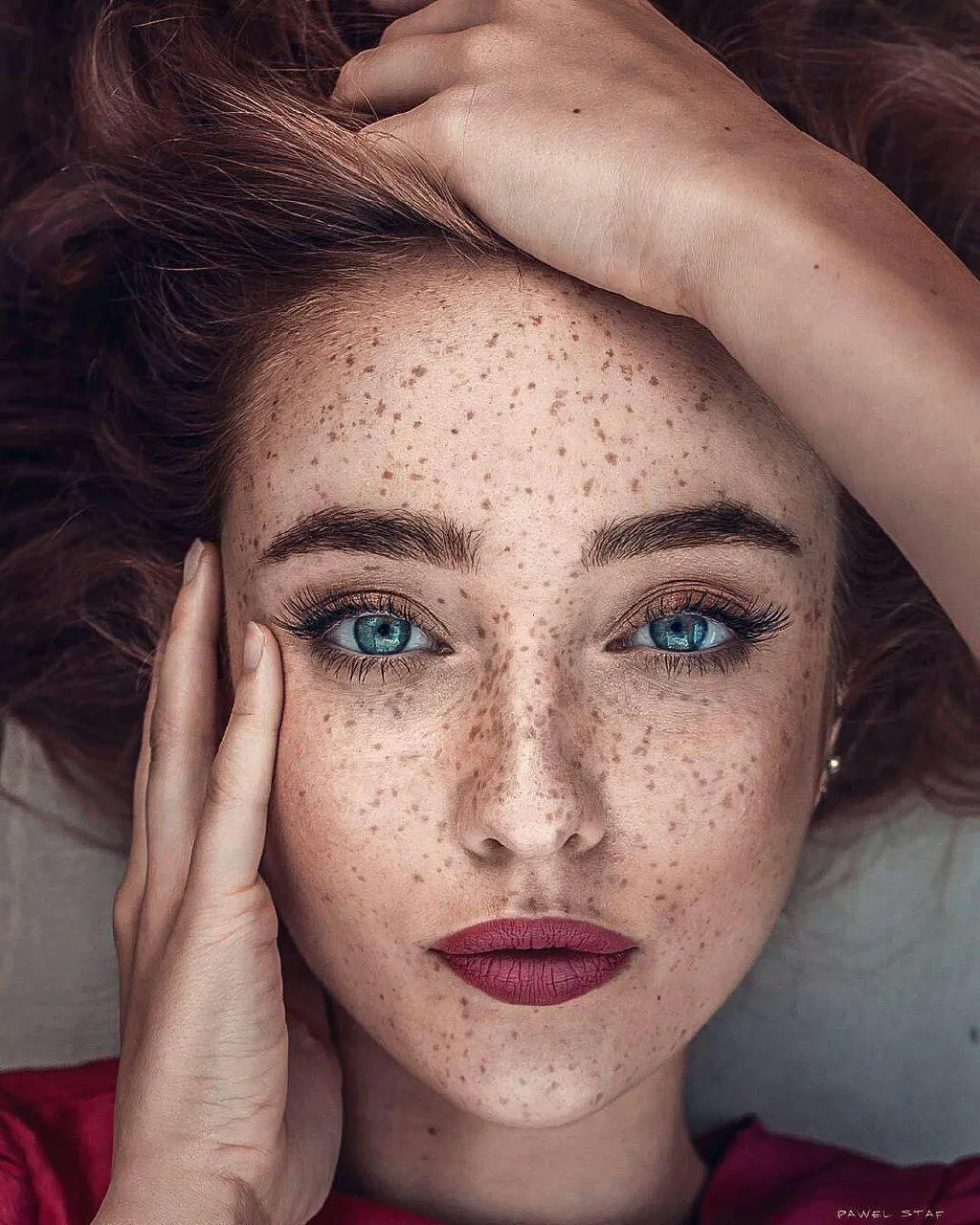 Freckled Woman with Red Hair Poses Close Up in Soft Light