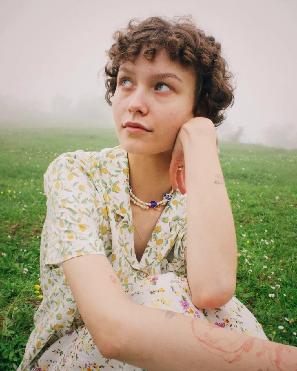 Girl with Short Curly Hair in a Floral Dress on Green Field