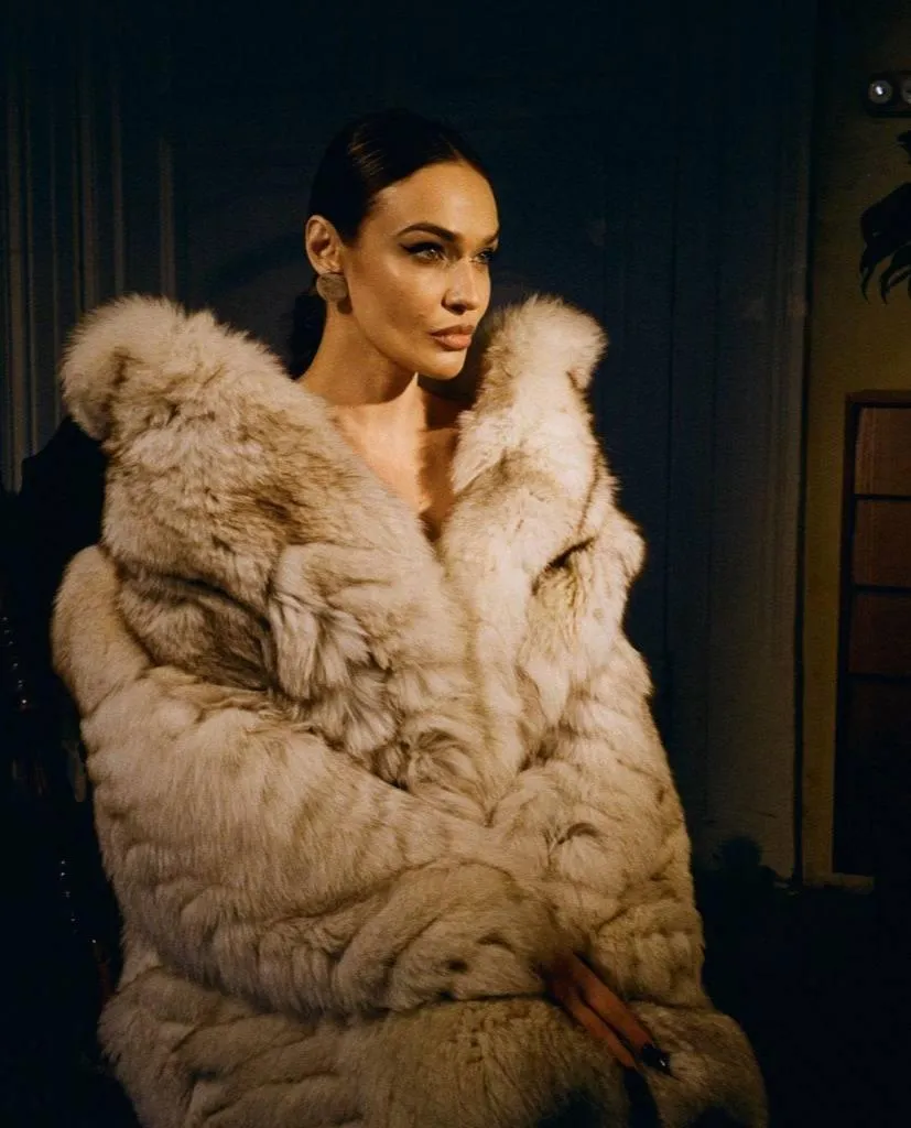 Glamorous woman in an oversized fur coat posing indoors