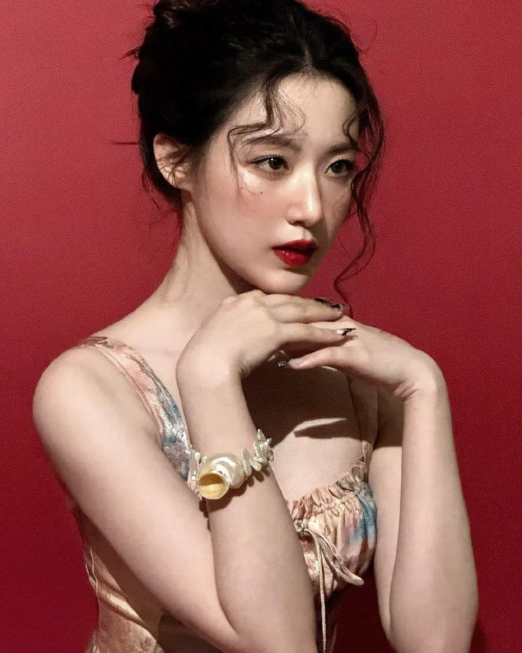 Glamorous Woman Poses Against a Red Backdrop with Rings