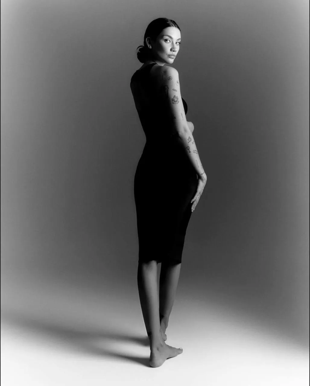 Graceful tattooed woman in a black dress posing elegantly