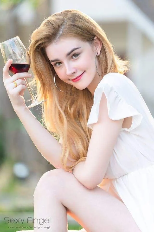 Happy woman in a white dress smiling while holding a drink