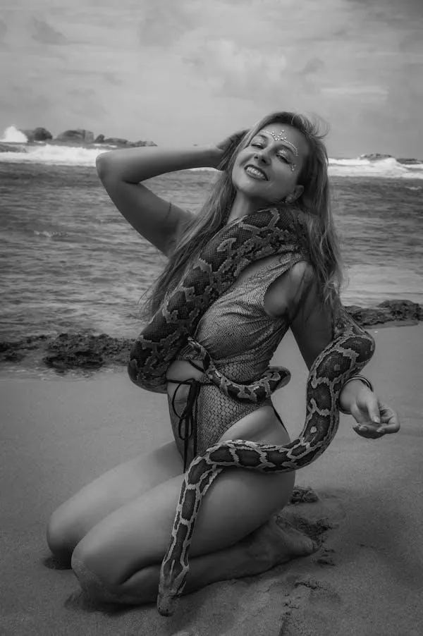Happy woman kneeling in water wearing a swimsuit with snake