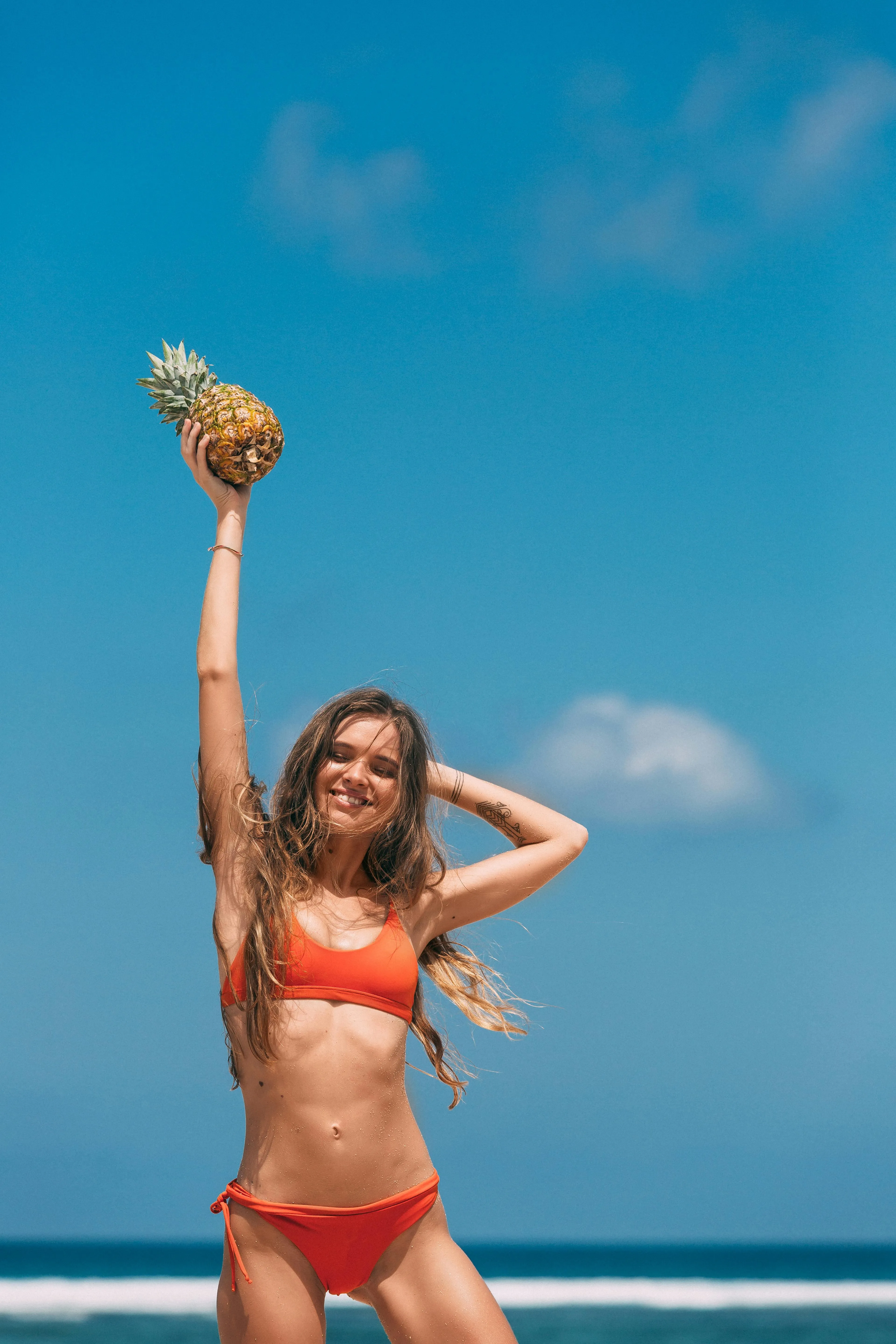 Joyful Woman in an Orange Bikini Holding a Pineapple High