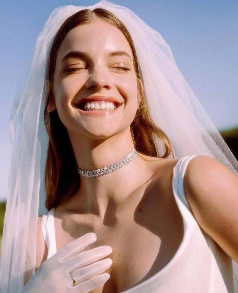 Joyful woman in bridal veil smiling brightly in sunlight