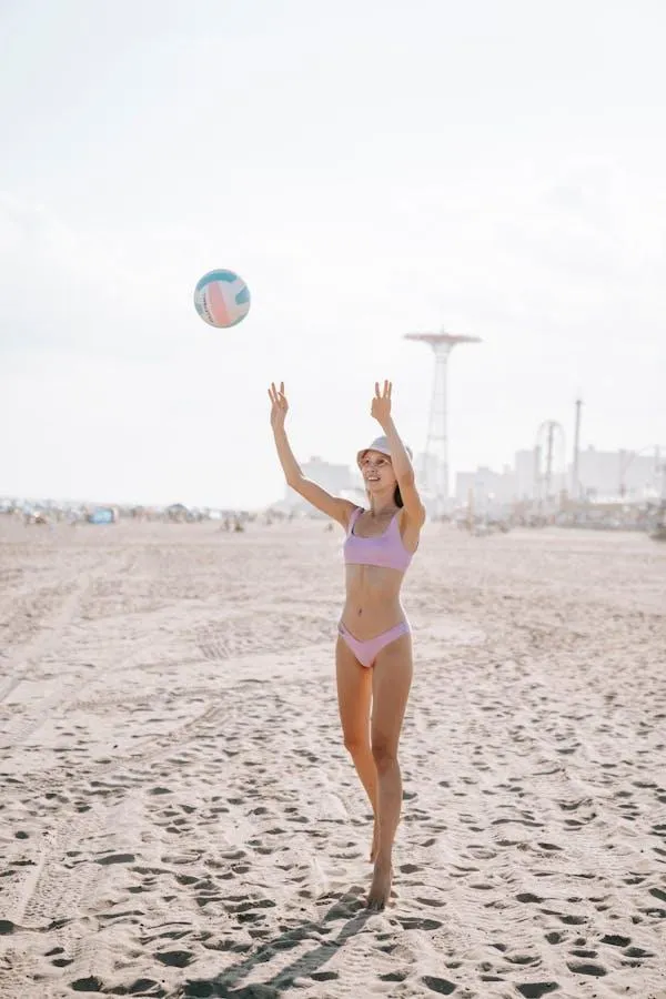 Joyful woman playing volleyball on the sandy beach shore