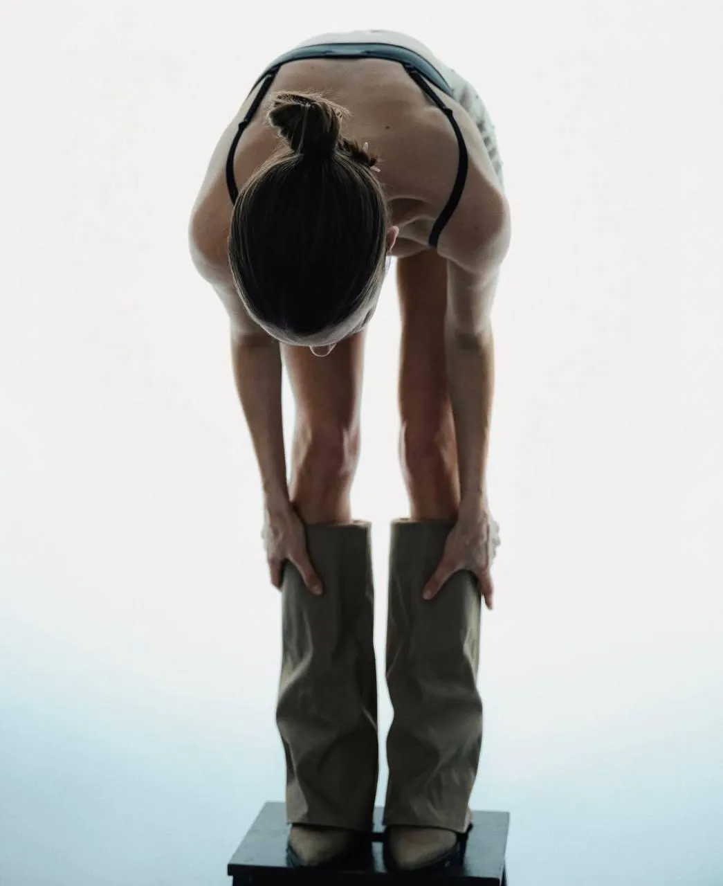 Minimalist artistic pose with a strappy top and wide boots