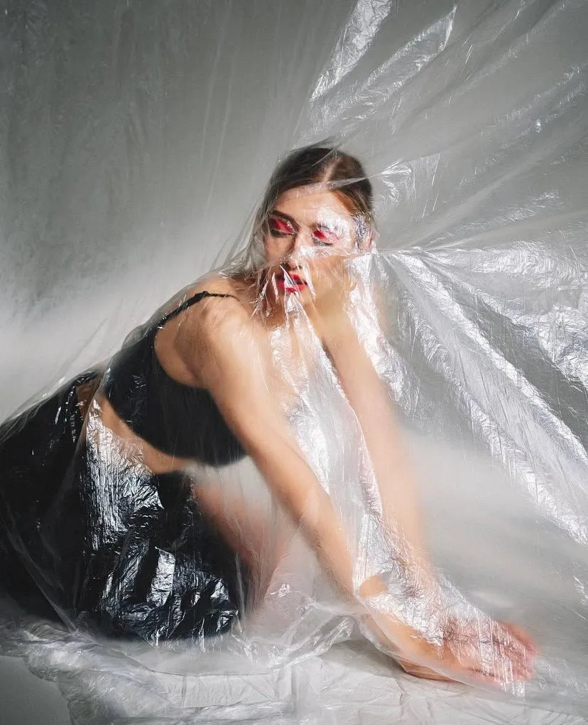 Model in a Black Outfit Wrapped in Translucent Plastic Image