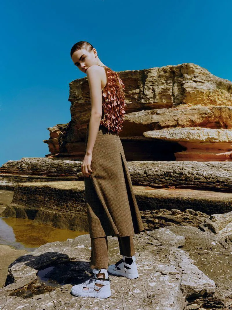 Model in a Brown Outfit Posing by a Layered Rock Cliff Image