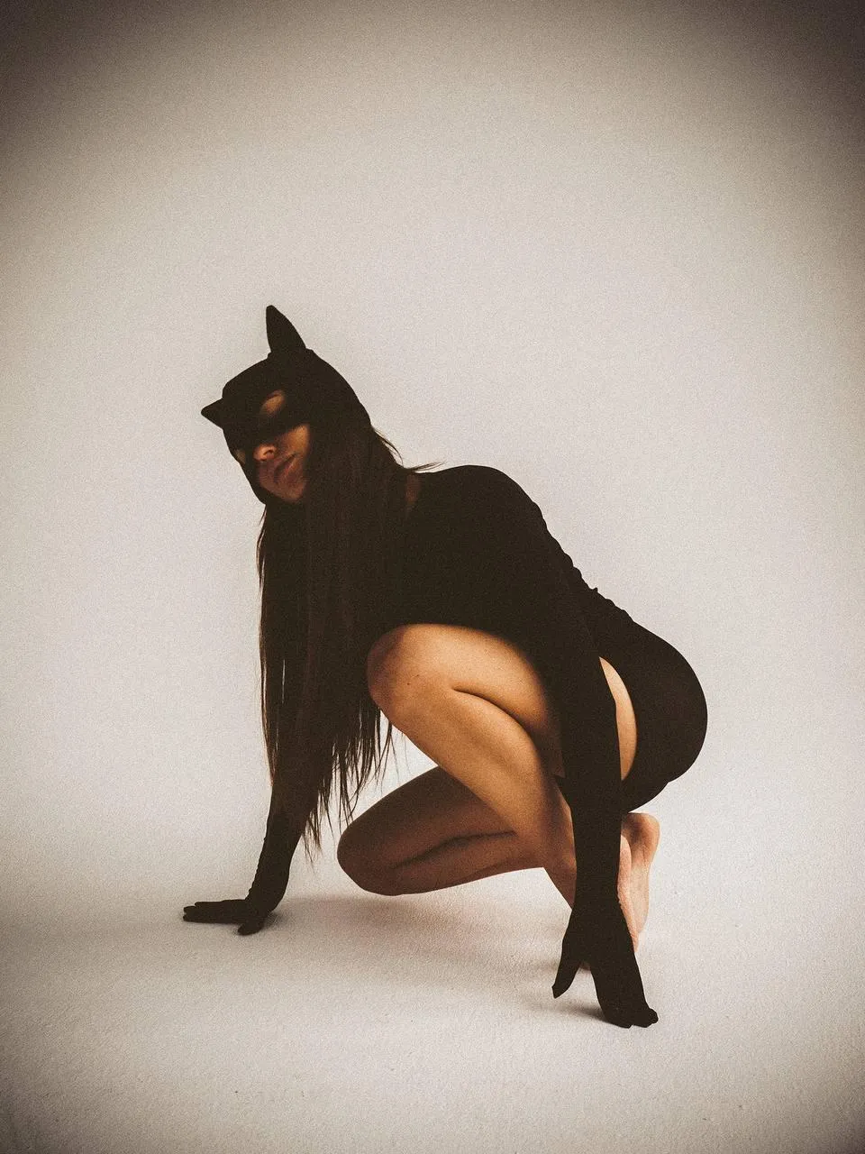 Model in a Dark Outfit Crouching with a Bold Feline Pose