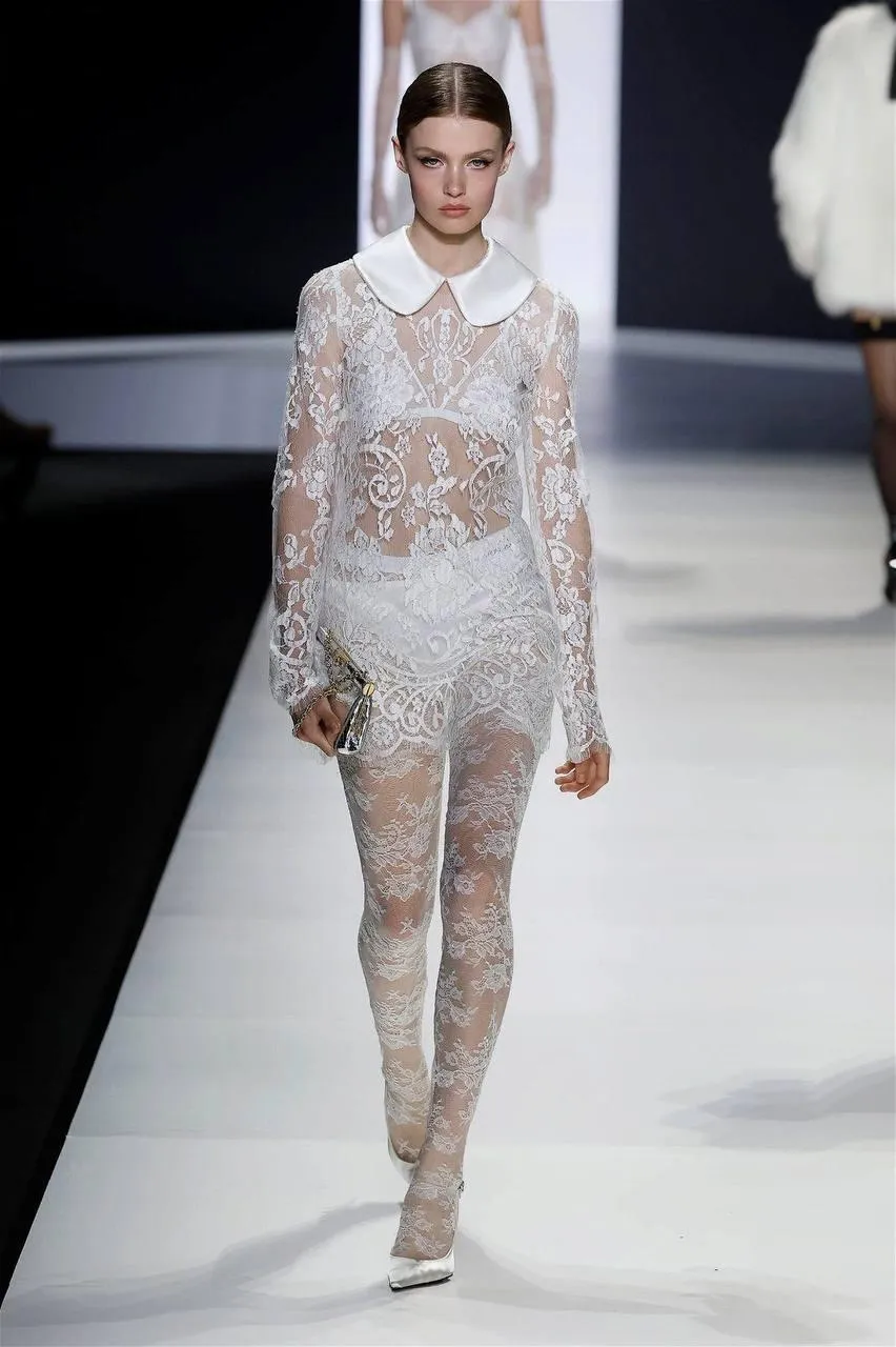 Model Walks Confidently Down a Runway in a White Outfit