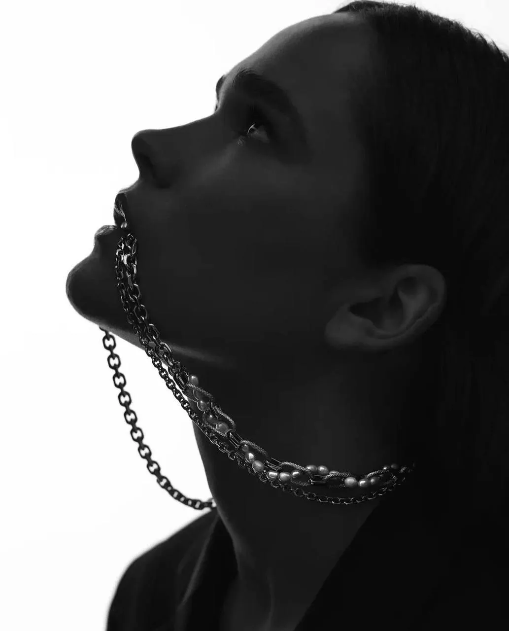 Monochrome image of a woman chain on her mouth looking up