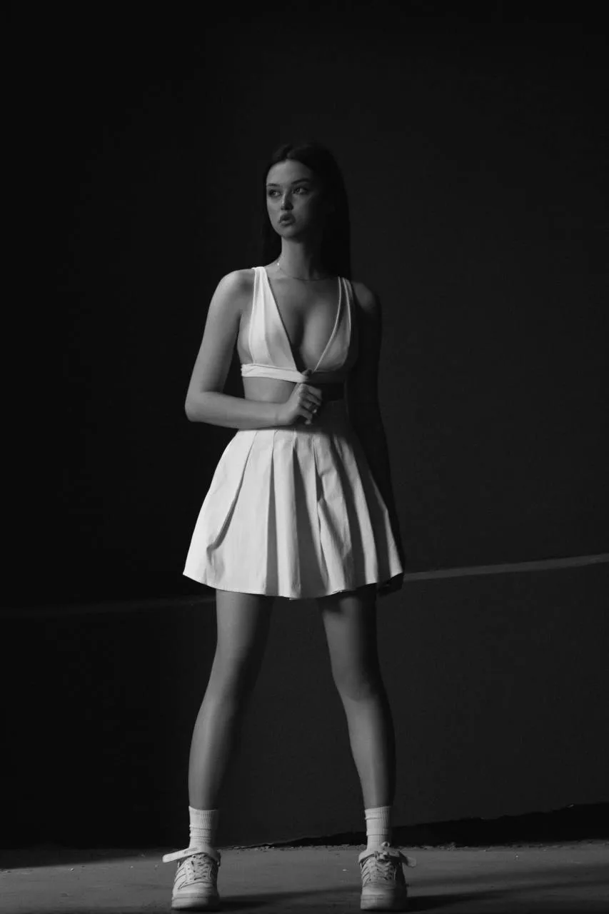 Monochrome image of a woman standing on the studio wallpaper