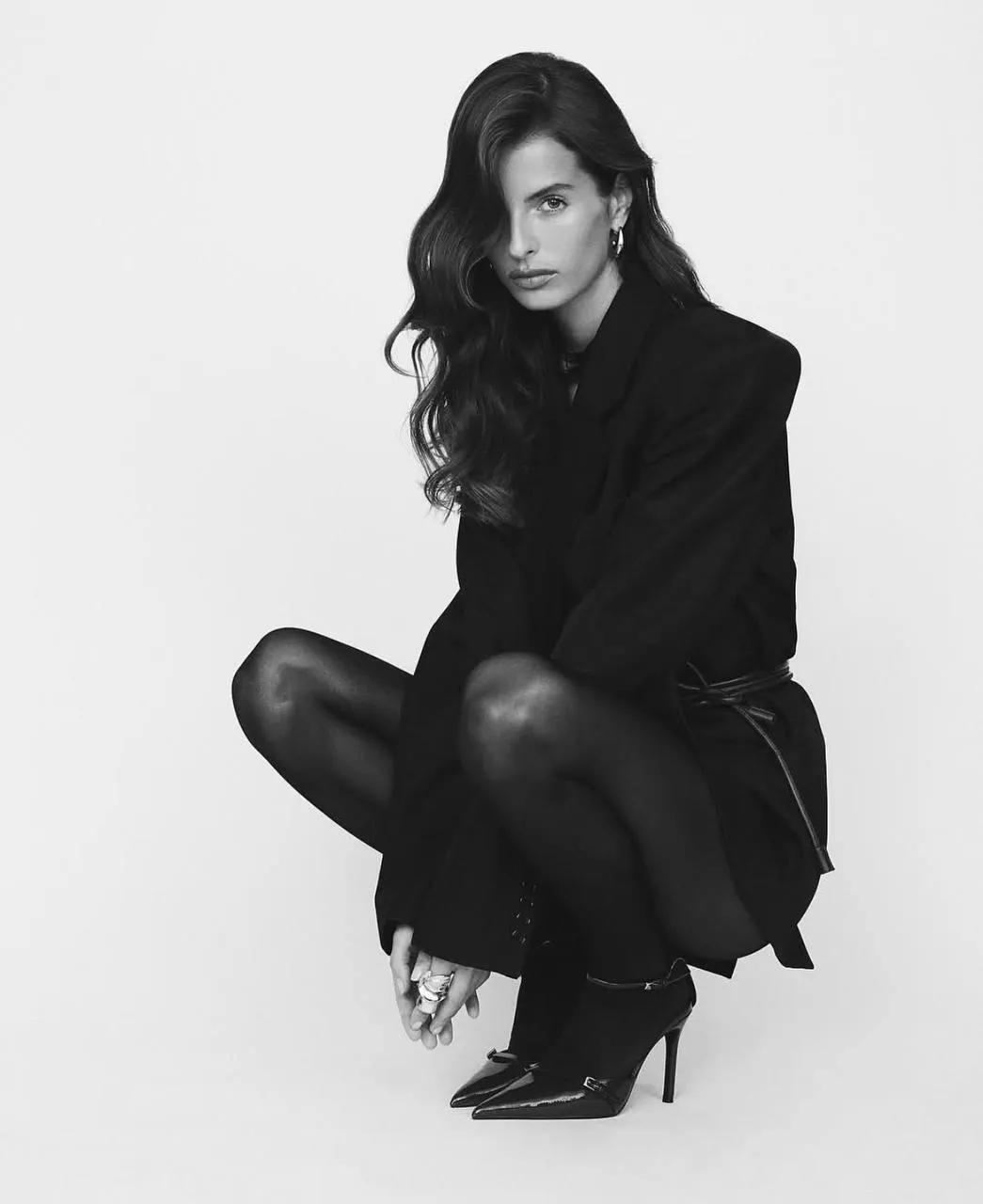 Monochrome of a young woman squatting on the studio floor