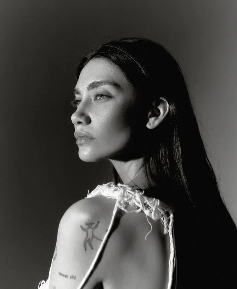 Monochrome of tattooed woman looking back with glowing face