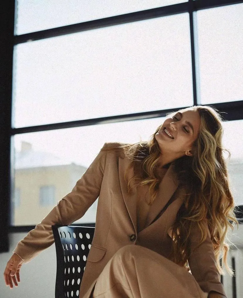 Office Chic Style in a Tan Suit Sitting by a Large Window