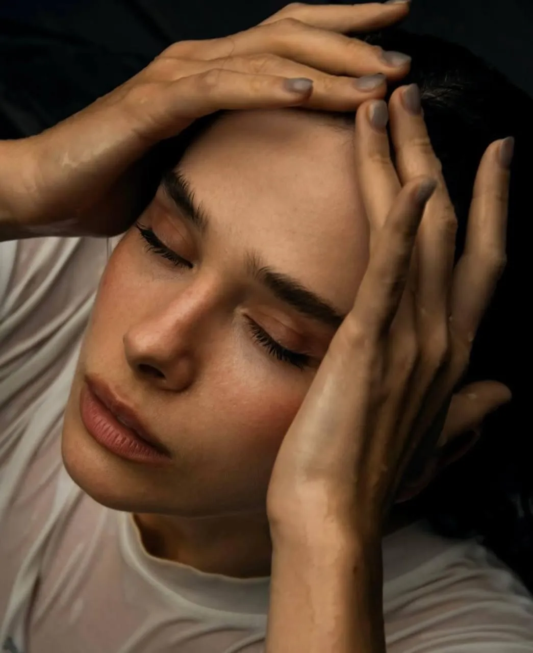 Pensive woman resting her face on her hands in soft light