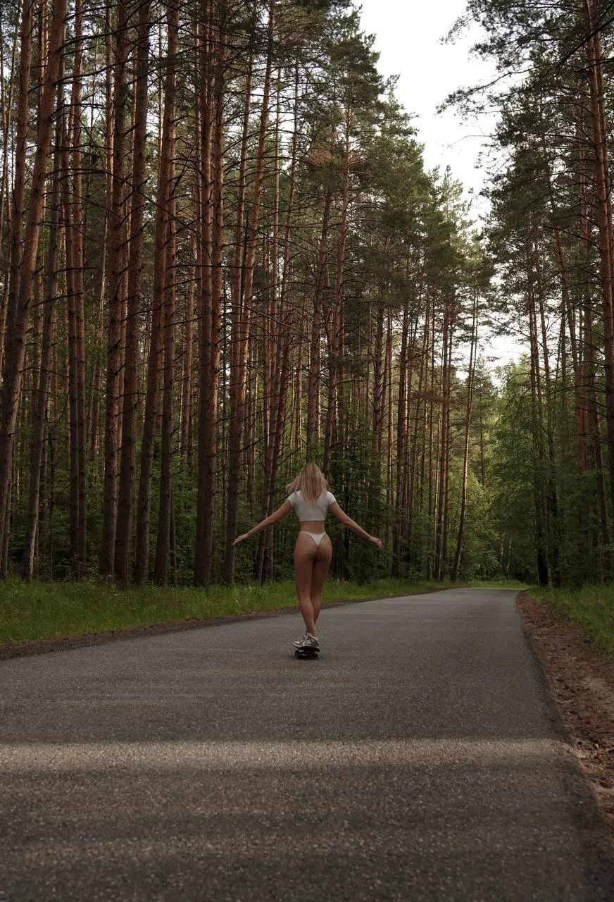 Person Walking on a Forest Road with Tall Trees HD Wallpaper