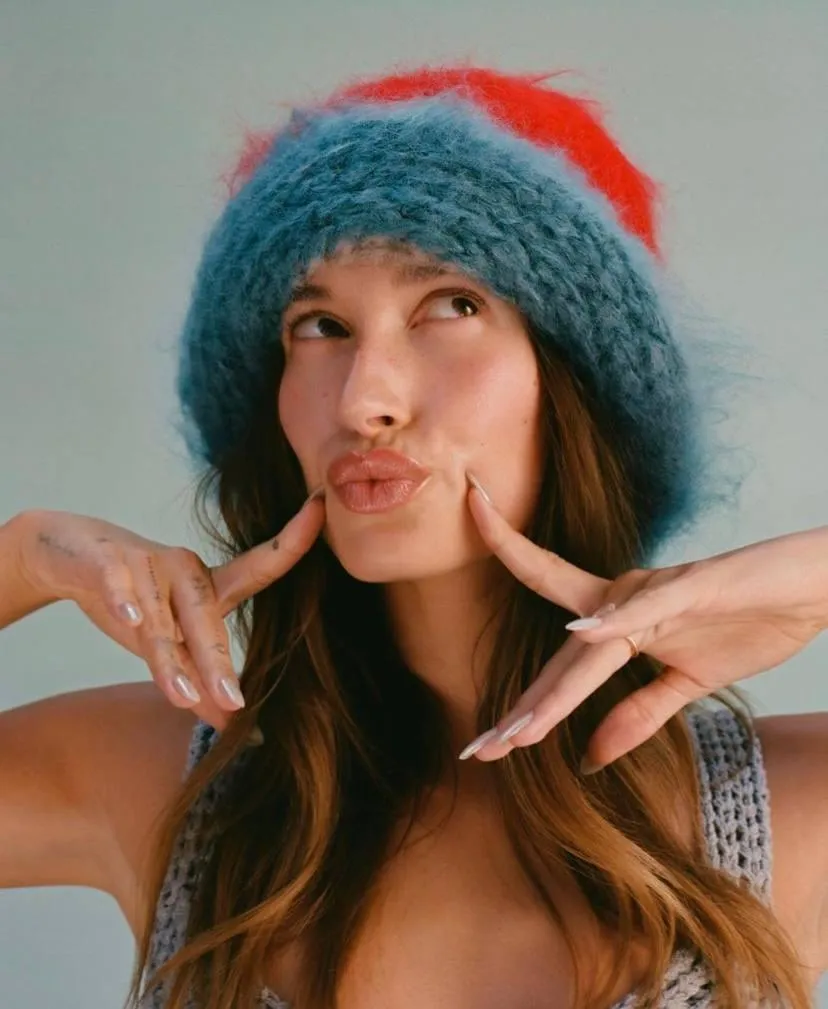 Playful woman wearing colorful winter hat making silly face
