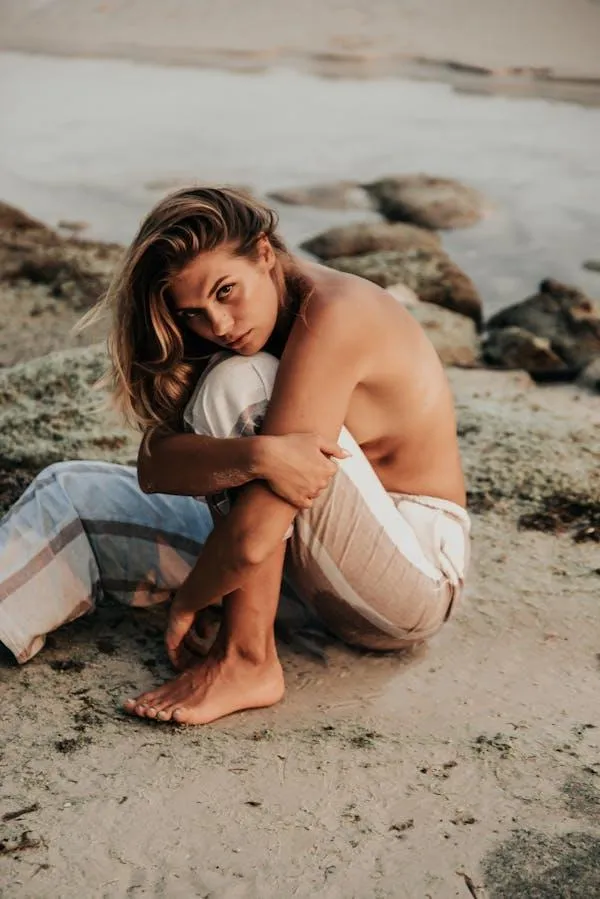 Relaxed woman sitting barefoot outdoors on a rock wallpaper