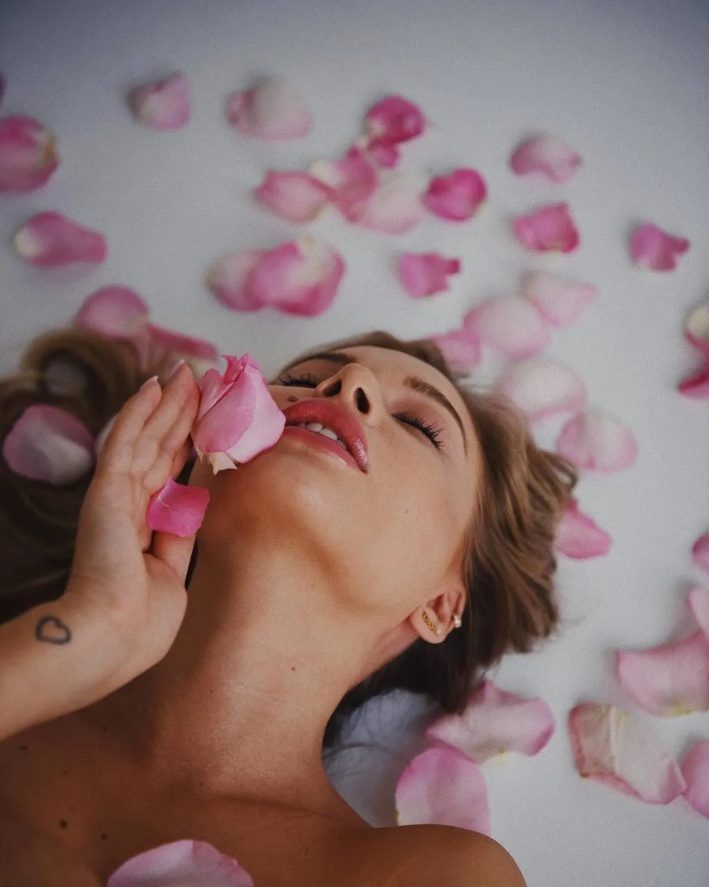 Relaxed Woman with Rose Petals Lying on the Floor Wallpaper