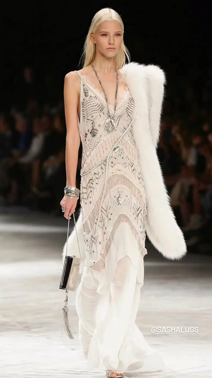 Runway model walking in glamorous white dress with fur stole