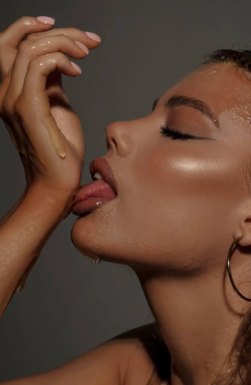 Sensual portrait of woman licking her hand with bold makeup