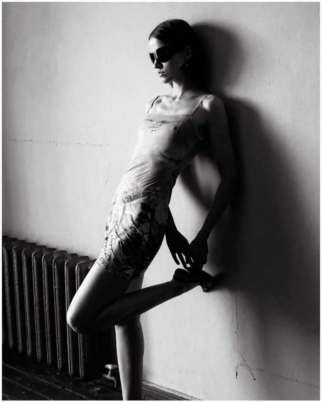 Shadowed Monochrome Photo of a Woman Leaning on a Radiator