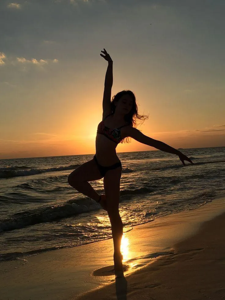 Silhouette of a woman dancing on the beach at golden sunset
