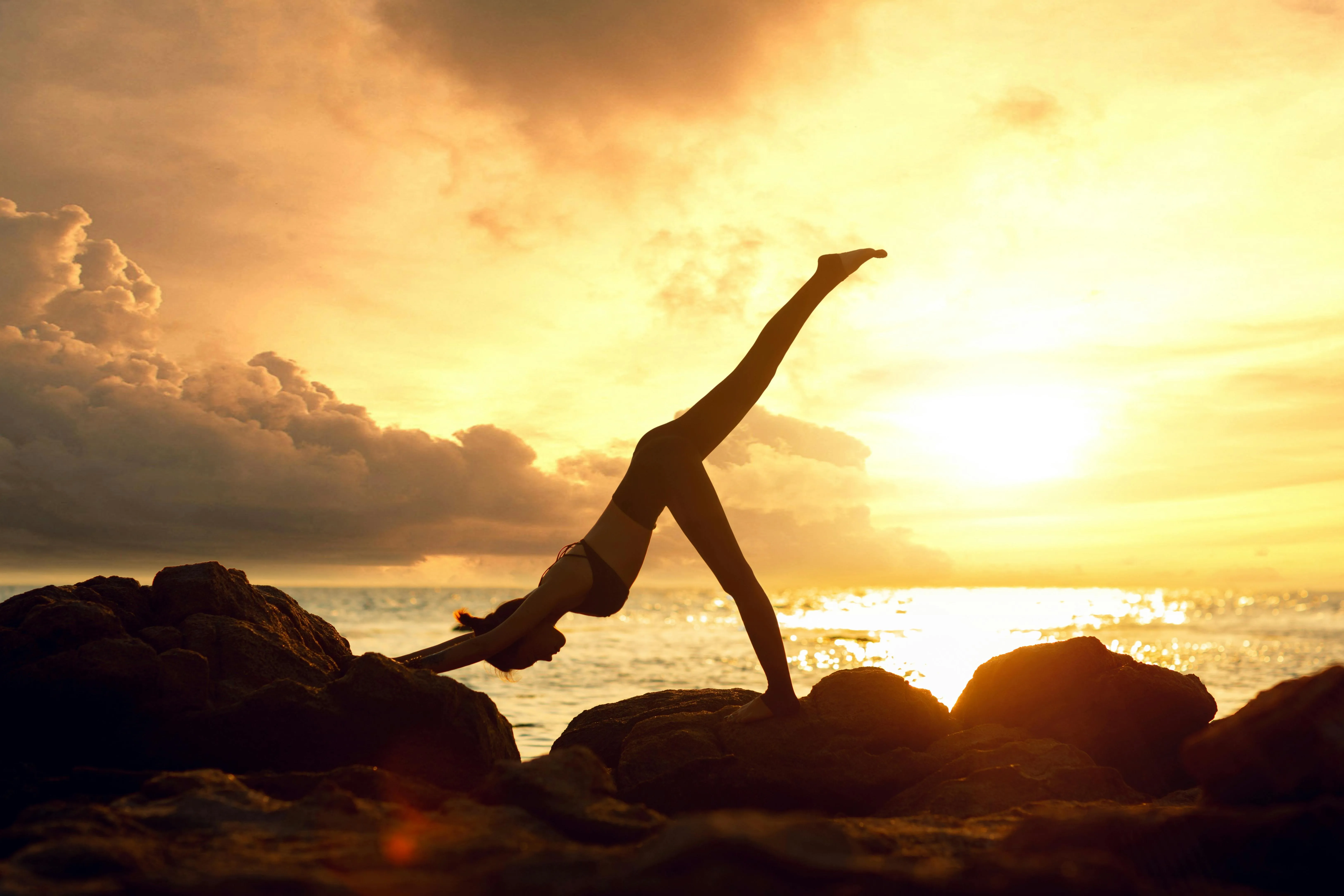 Silhouette of Woman Dancing During a Golden Sunset on Rocks