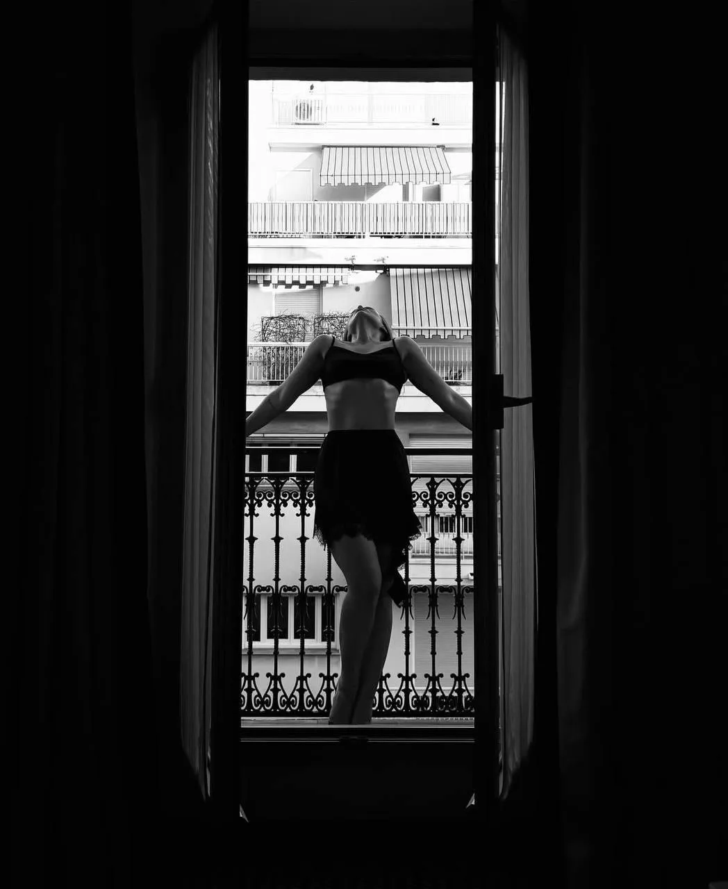 Silhouette of Woman Looking Out From Balcony in Black Dress