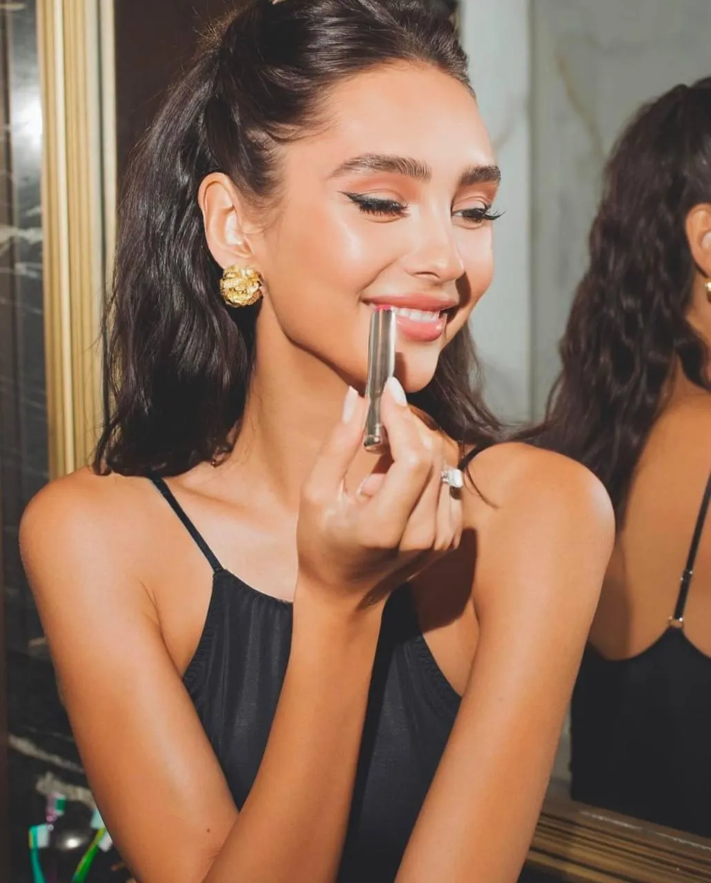 Smiling Woman Applying Lipstick in a Warm Lively Atmosphere