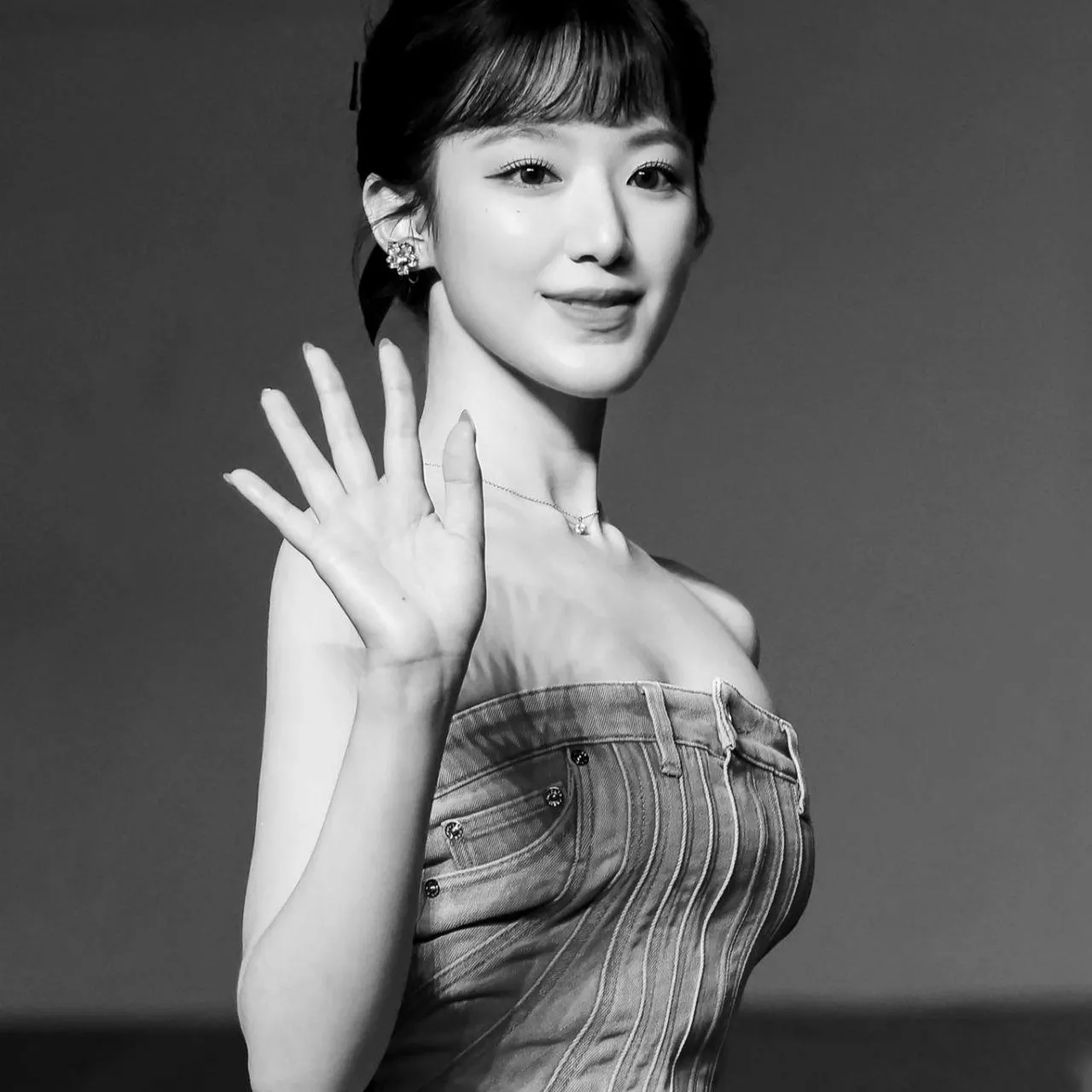 Smiling Woman in a Pleated Dress Waving at the Camera Image