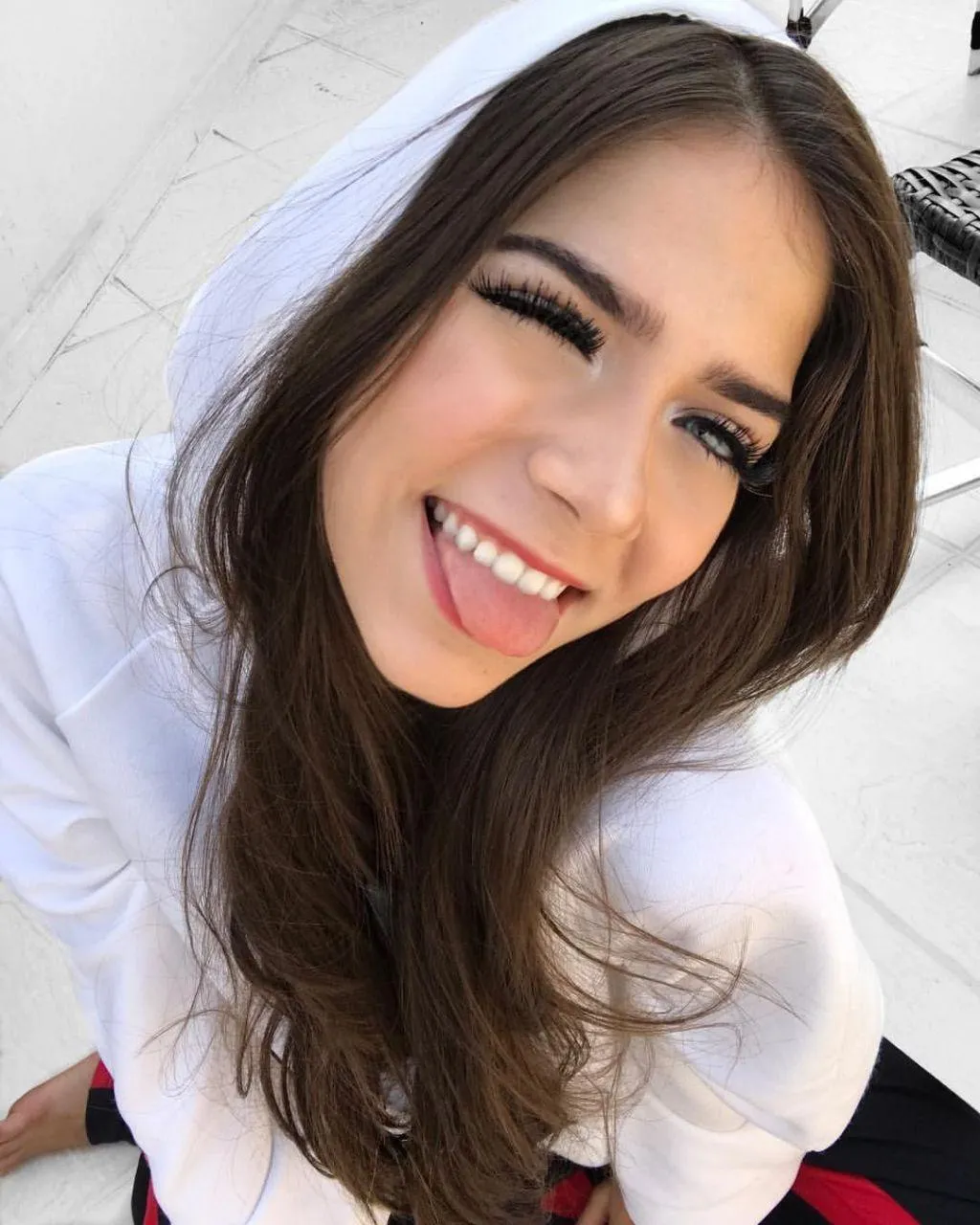Smiling Woman in a White Hoodie with Wind Blowing Her Hair