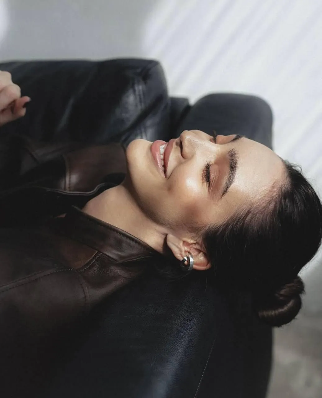 Smiling woman in leather jacket with wet hair posing indoors