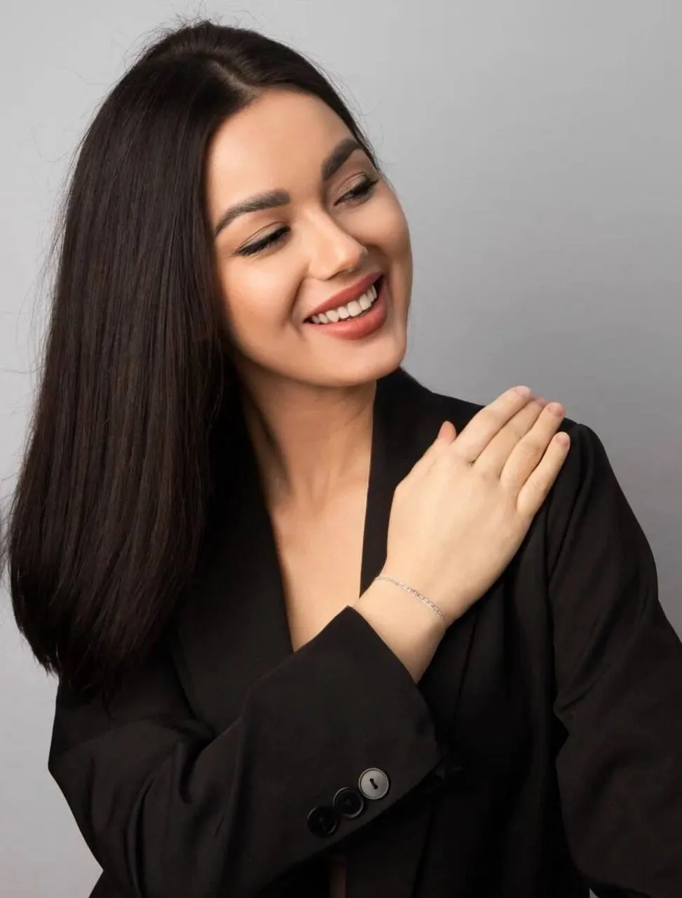 Smiling woman with straight hair in a black top looking side