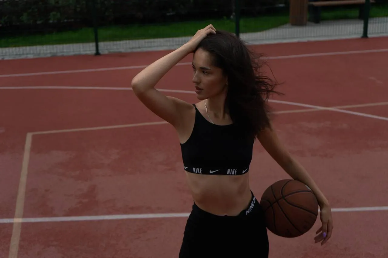 Sporty woman holding a basketball on a red outdoor court