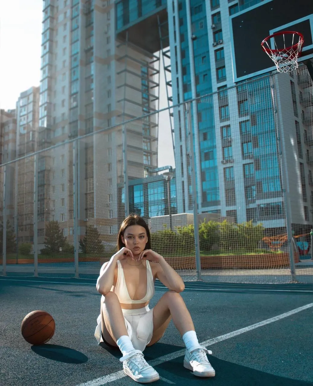 Sporty Woman with a Basketball Poses on a City Court Street