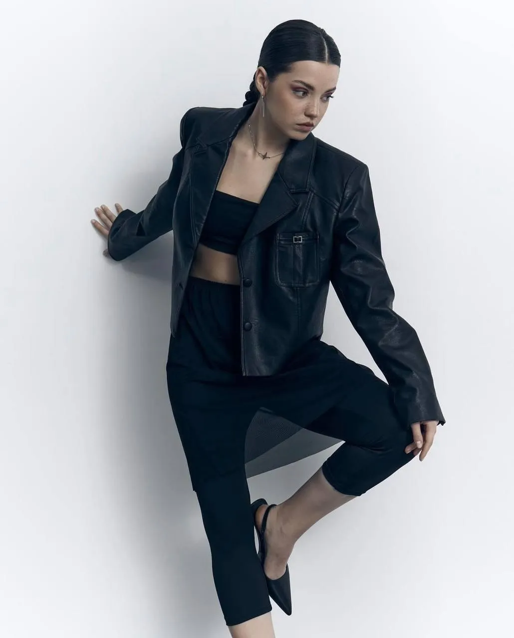 Stylish woman in a black jacket and pants striking a pose
