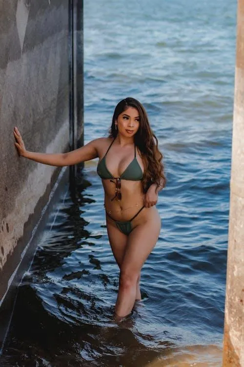 Stylish woman in a green bikini standing on the water image