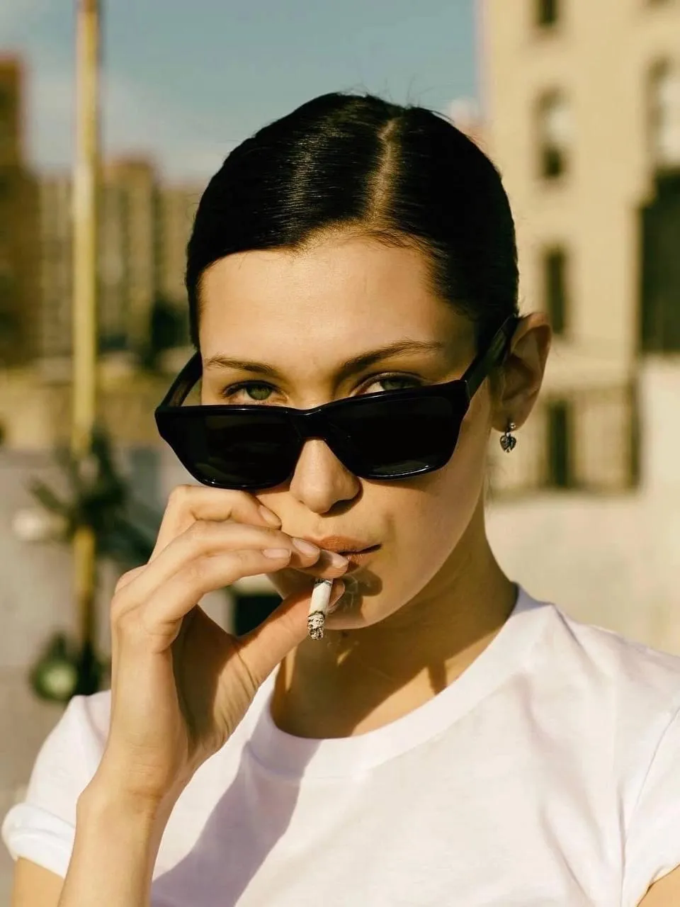 Stylish woman in sunglasses and a white top in sunny setting