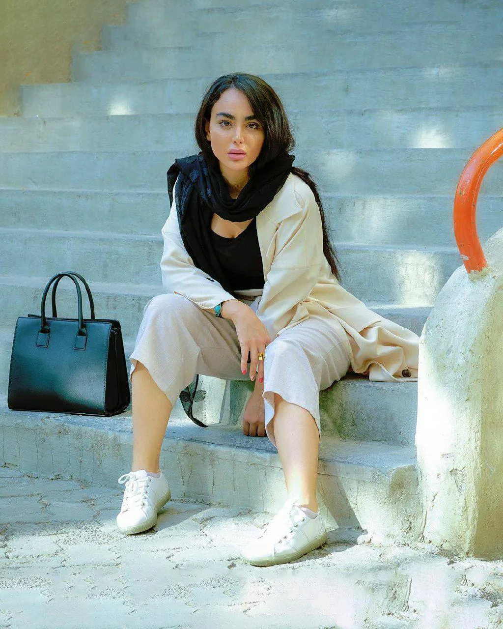 Stylish Woman Sitting on the Stairs with a Black Handbag