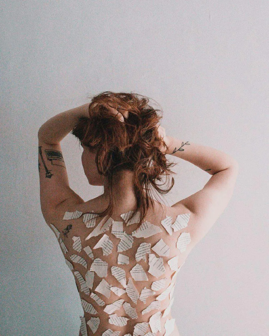 Stylish Woman with Curly Hair Posing Against a Plain Wall