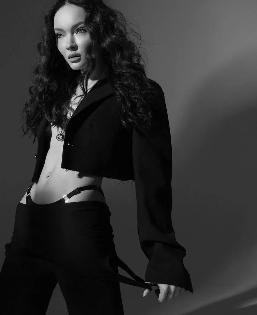 Sultry woman in a black dress standing in the studio setting